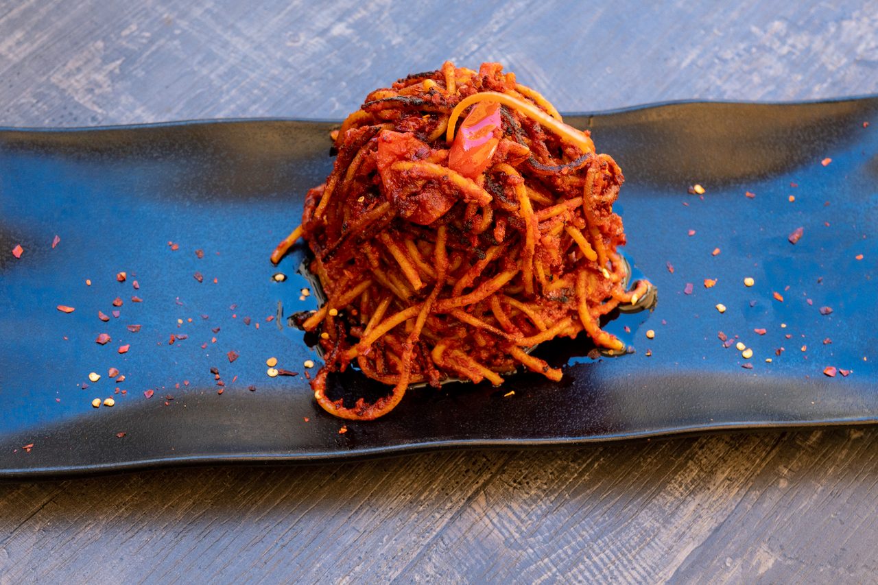 Spaghetti all'assassina croccanti su piatto rettangolare blu scuro con peperoncino sparso, La Locanda dell'Elfo